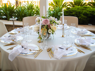 Wall Mural - Wedding banquet concept. Chairs and round table for guests, served with cutler and, flowers and crockery and covered with a tablecloth