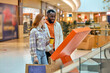 © Roman - Family doing shopping at mall Smiling happy couple carries shopper bags during great sales walking holding buying clothes In modern Contented Customers In Mall