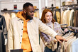 © Roman - afro handsome guy helps to choose a jacket, sweater for his ginger girlfriend at shop, showroom. close up side view photo,