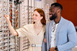 © Roman - cheerful couple enjoying spending time at optics, close up photo. woman wants to put on new trendy spectacles , sale black friday, cheep prizes, bargains, business, trade