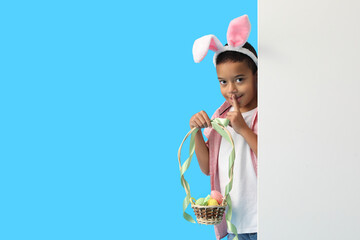 Sticker - Little African-American boy with basket of Easter eggs showing silence gesture on color background