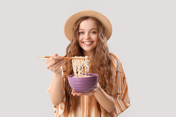 Canvas Print - Young woman with bowl of Chinese noodles on light background