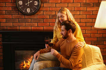 Poster - Lovely couple with glasses of wine spending time together near fireplace at home