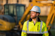 © Volodymyr - Worker in helmet on site construction. Man excavator bulldozer worker. Construction driver worker with excavator on the background. Construction worker with tractor or construction at building.
