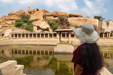 Wall Mural - Woman tourist enjoy view of Pushkarani an ancient water reservoir at Hampi Karnataka, India.