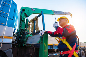 Asian supervisor or foreman with mobile crane at construction site.