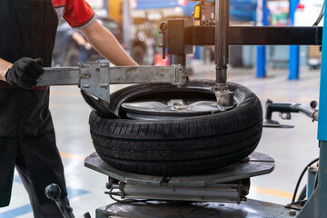 Wall Mural - A male car mechanic changing tires and balancing car wheel on balancer at auto repair shop for the auto industry. Automobile industry. Machine for removing rubber from the wheel disc.