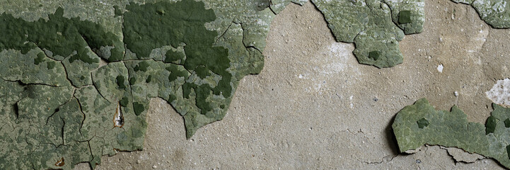 Peeling paint on the wall. Panorama of a concrete wall with old cracked flaking paint. Weathered rough painted surface with patterns of cracks and peeling. Wide panoramic grungy texture for background