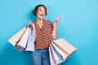 Leinwandbild Motiv Photo of adorable excited lady dressed print shirt holding shoppers showing looking empty space isolated blue color background