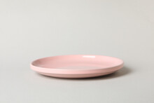 Empty pink plate on gray background, close up