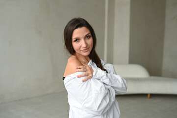 Young beautiful brunette woman in white shirt, stylish and minimalistic portrait in light colors