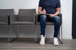 © Westend61 - Man filling form sitting on chair in waiting room