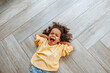 © Westend61 - Cute girl yawning and lying on wooden floor at home