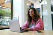 © Westend61 - Smiling young freelancer with messy hair using laptop at cafe