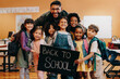 © Jacob Lund - Teacher and his primary school class holding a back to school sign, excited to start a new year