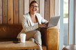 © Jacob Lund - Happy business woman sitting in a cafe and using a laptop