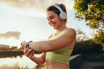 sports woman choosing a fitness playlist using a smartwatch outdoors