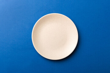 Wall Mural - Top view of isolated of colored background empty round beige plate for food. Empty dish with space for your design