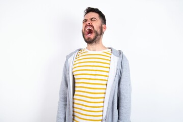 Wall Mural - Young caucasian mán wearing trendy clothes over white background angry and mad screaming frustrated and furious, shouting with anger. Rage and aggressive concept.