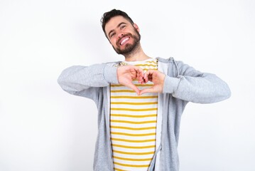 Wall Mural - Young caucasian mán wearing trendy clothes over white background smiling in love doing heart symbol shape with hands. Romantic concept.