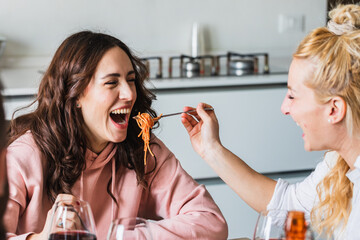 Couple of friends having fun eating with spaghetti