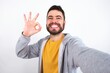 © Jihan - Portrait of pretty cheerful Young caucasian mán wearing trendy clothes over white background make selfie show okey symbol
