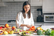 © puhimec - Attractive young woman cutting vegetables for salad in the kitchen.