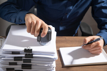 Poster - Businessman puts a stamp on the documents in the office.