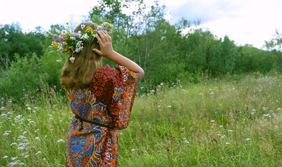 Wall Mural - girl in flower wreath on green meadow, abstract natural background. rear view. Floral crown, symbol of summer solstice. ceremony on Midsummer, wiccan Litha sabbat. pagan slavic holiday Ivan Kupala.