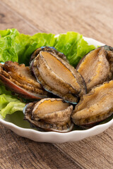 Wall Mural - Delicious raw abalone in a plate on wooden table background.