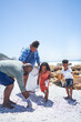 © Caia Image - Family volunteering, cleaning litter from sunny summer beach