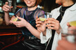 © LIGHTFIELD STUDIOS - Cropped view of smiling multiethnic women holding tequila and lime in bar.