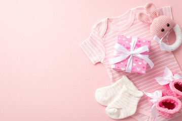 Wall Mural - Gender reveal party concept. Top view photo of pink giftbox with bow infant clothes bodysuit tiny socks knitted booties and bunny rattle toy on isolated pastel pink background