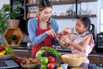 Wall Mural - Young mother teach daughter in the kitchen learn online cooking clean food from the laptop computer