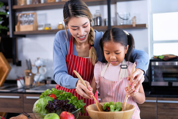 Wall Mural - Young mother teach daughter in the kitchen learn online cooking clean food from the laptop computer