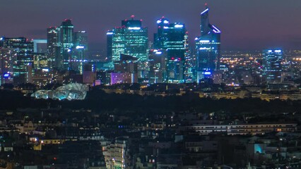 Wall Mural - Aerial Night timelapse view of Paris City and Seine river shot on the top of Eiffel Tower observation deck. Evening illumination. Modern skyscrapers of business district