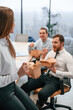 © standret - Woman is leaning on the table. Group of coworkers are eating food from eco boxes in the office together