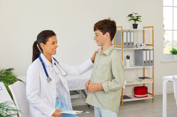 Smiling female doctor comforting boy patient in consultation in medical clinic. Caring woman general practitioner or pediatrician supporting and cheering cute preteen boy. Pediatric appointment