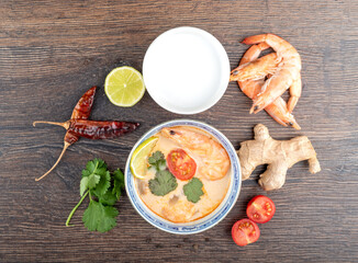 Tom Yum Kung, shrimp soup and ingredients on a wooden background, Thai food in a bowl, top view.