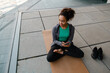 © Drobot Dean - African girl using smartphone while doing yoga stretching exercises outdoors