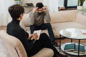 Man talking to psychologist about his problems while sitting on couch