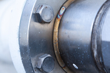 A section of a welded pipe with a stainless steel flange with screwed-in bolts.