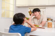 © tonefotografia - Young Asian father angry his son about eat vegetables in kitchen at home