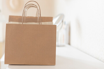 Recycled shopping craft paper bags on the white table. Close up. Copy space