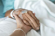 © Phimchanok - inpatient hand holding from relative or family, palm of an old man clasp his family member for energy support while stay in hospital for modern and high technology medical treatment by skillful doctor