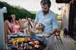 © Halfpoint - Father with little son grilling outside during family summer garden party.