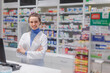 Portrait of young pharmacist selling medication in pharmacy.