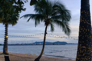 light bulbs on string wire decoration at the party event festival on the beach at sunset. Outdoor holiday background. Copy space.