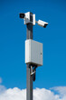 white security cameras on a gray metal pole on a bright sunny day
