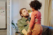 © pressmaster - Young father sitting in front of his cute listtle son holding toy airplane, looking at him and saying something on his coming back home